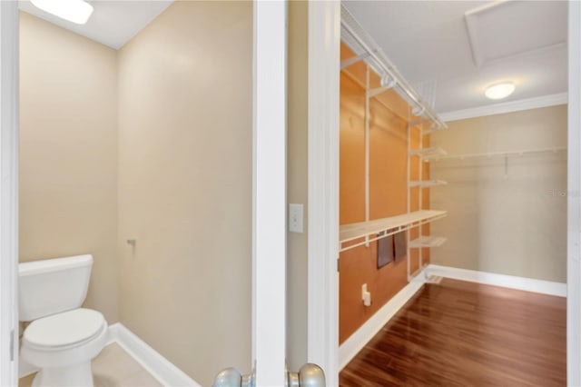 bathroom featuring hardwood / wood-style flooring, ornamental molding, and toilet