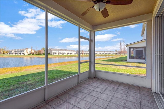 unfurnished sunroom featuring a water view, ceiling fan, and a healthy amount of sunlight