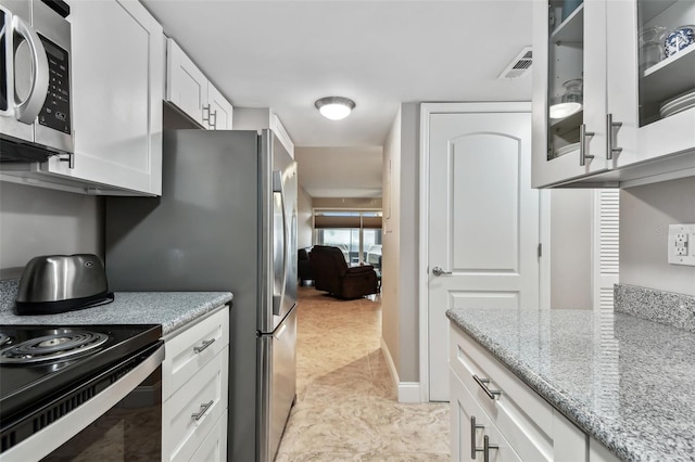 kitchen featuring light stone counters, light tile patterned flooring, and white cabinets