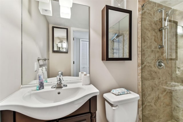 bathroom featuring tiled shower, vanity, and toilet