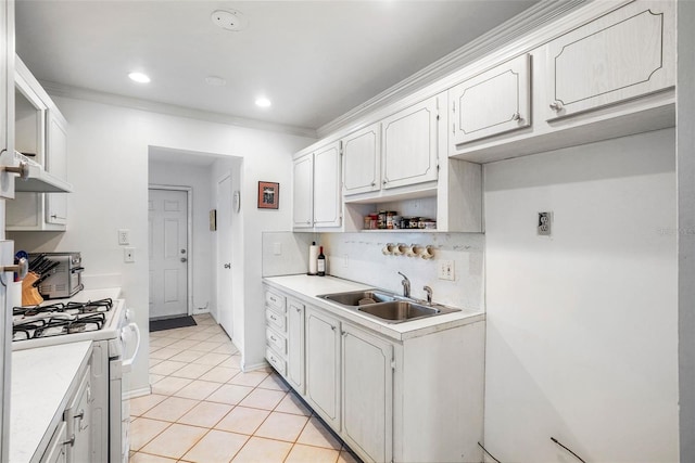 kitchen with light tile patterned floors, ornamental molding, sink, and white cabinets