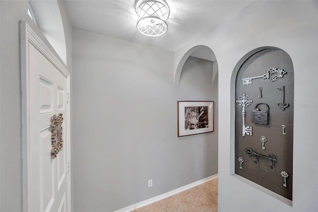 corridor with light tile patterned floors and a textured ceiling