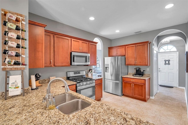 kitchen with sink, light tile patterned flooring, light stone countertops, and appliances with stainless steel finishes