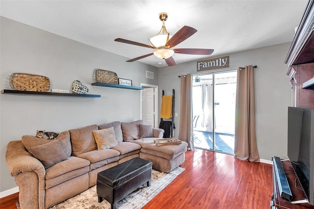 living room with a textured ceiling, wood-type flooring, and ceiling fan