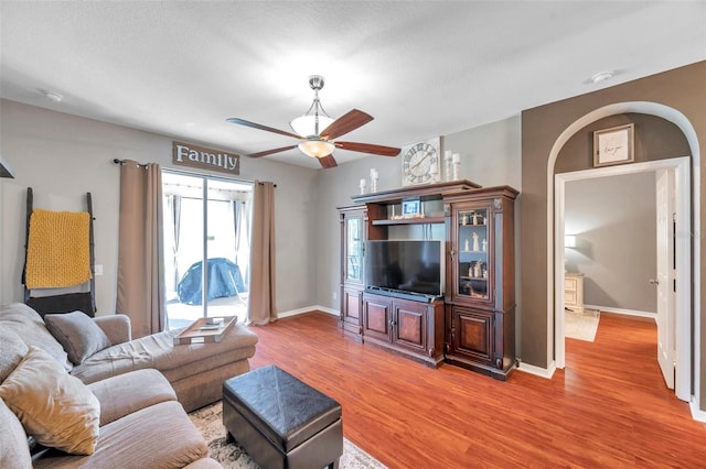 living room featuring hardwood / wood-style flooring, ceiling fan, and a textured ceiling