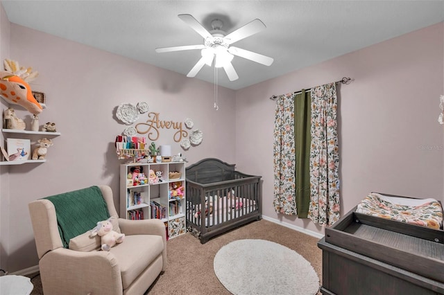 bedroom featuring a crib, light colored carpet, and ceiling fan