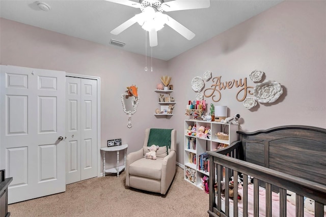 carpeted bedroom with a nursery area, ceiling fan, and a closet