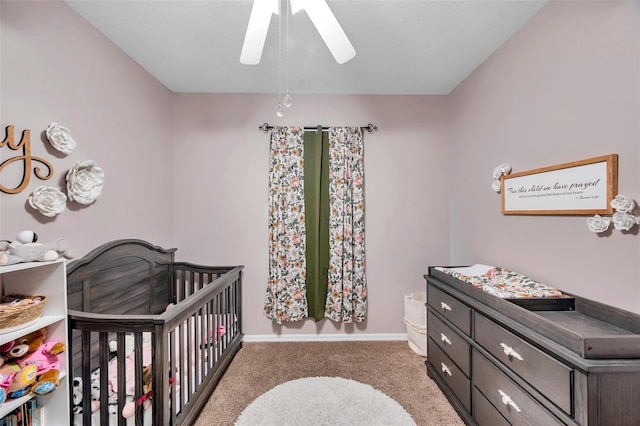 bedroom featuring a nursery area, ceiling fan, and carpet flooring