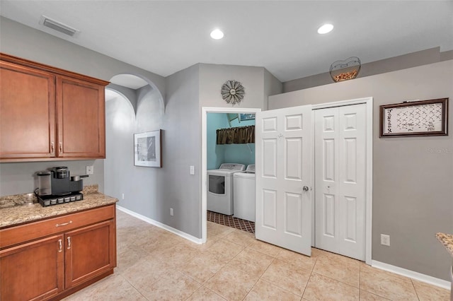 kitchen featuring light stone counters, washer and clothes dryer, and light tile patterned floors