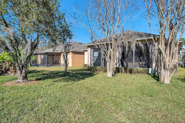 rear view of property featuring a sunroom and a lawn