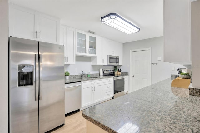 kitchen with sink, white cabinetry, light hardwood / wood-style flooring, stainless steel appliances, and light stone countertops