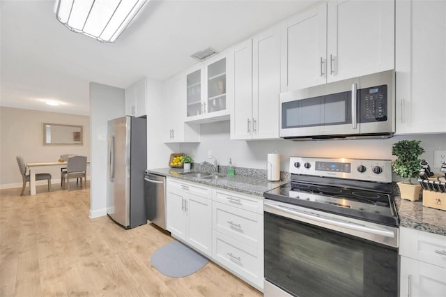 kitchen with light stone counters, stainless steel appliances, sink, and white cabinets