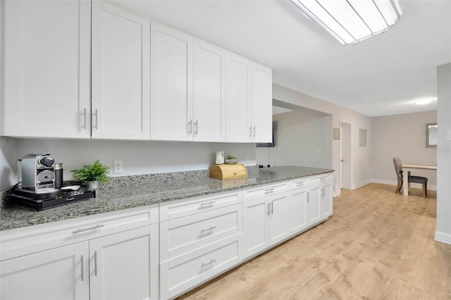 kitchen with white cabinetry, light stone countertops, and light hardwood / wood-style floors