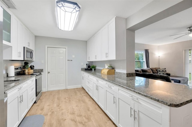 kitchen with stone counters, light wood-type flooring, white cabinets, and appliances with stainless steel finishes