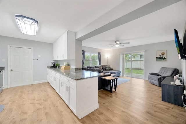 kitchen featuring white cabinetry, light hardwood / wood-style flooring, kitchen peninsula, and dark stone countertops