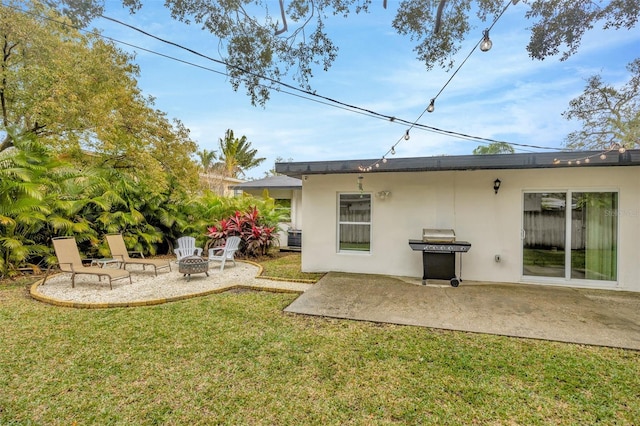 back of property with a fire pit, a patio area, and a lawn