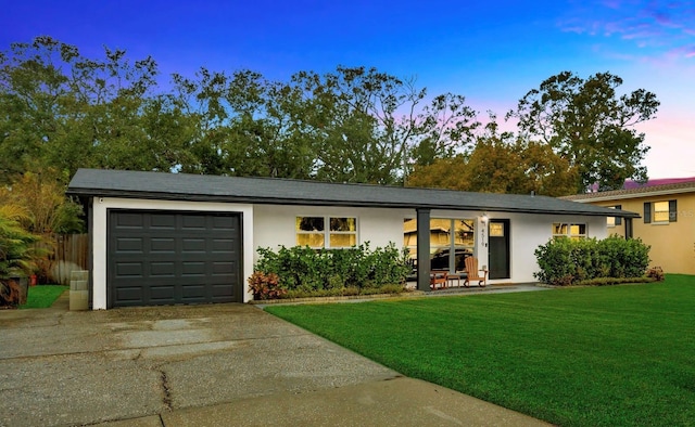 ranch-style home with a garage and a lawn