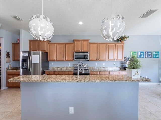 kitchen featuring appliances with stainless steel finishes, decorative light fixtures, a chandelier, and a kitchen island with sink