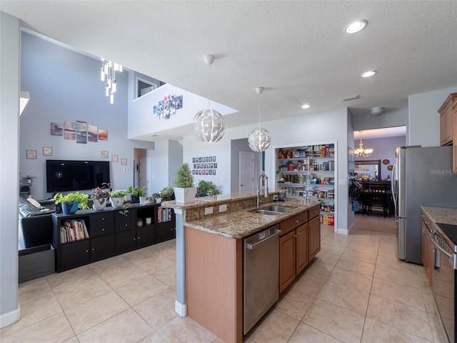 kitchen featuring pendant lighting, sink, appliances with stainless steel finishes, an island with sink, and a chandelier