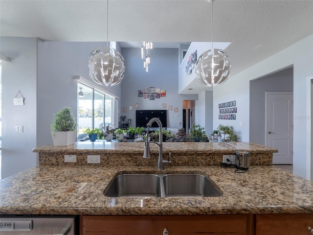 kitchen with sink, a notable chandelier, a textured ceiling, stone countertops, and decorative light fixtures