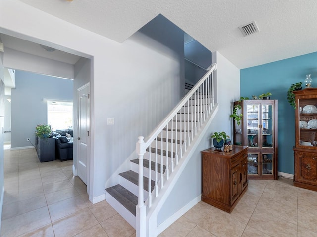 stairway featuring tile patterned flooring and a textured ceiling