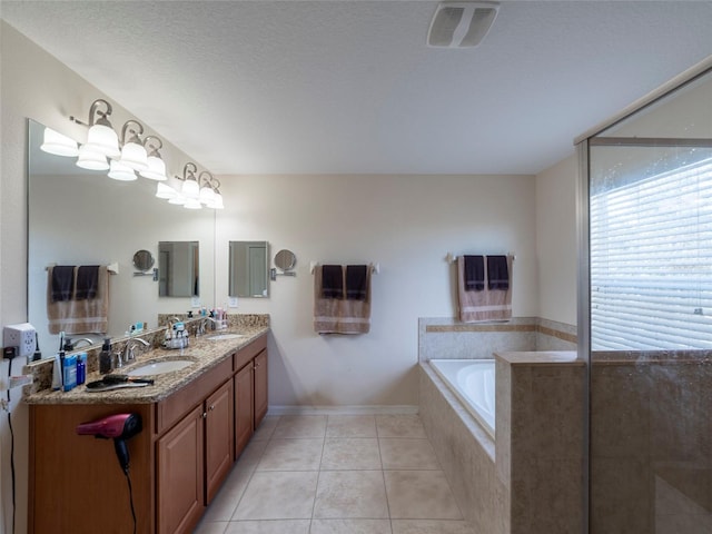 bathroom featuring vanity, a relaxing tiled tub, tile patterned floors, and a textured ceiling