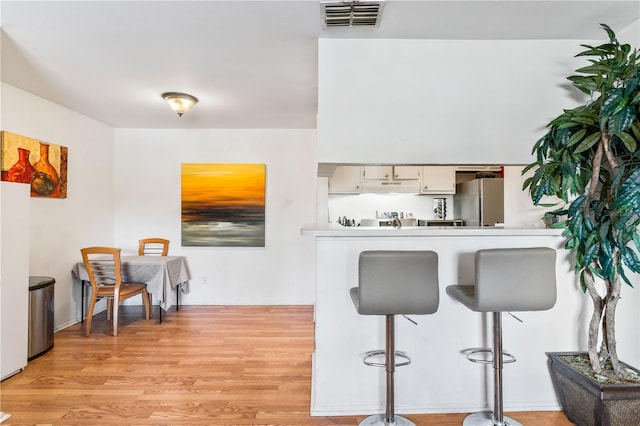 1400 Gandy Blvd N Unit 506, Saint Petersburg, FL 33702 - kitchen with light wood-type flooring, white cabinets, stainless steel refrigerator, and kitchen peninsula
