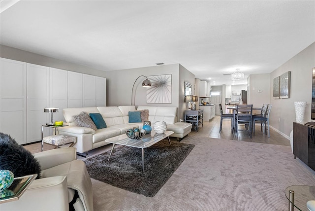 living room with light carpet, visible vents, and baseboards