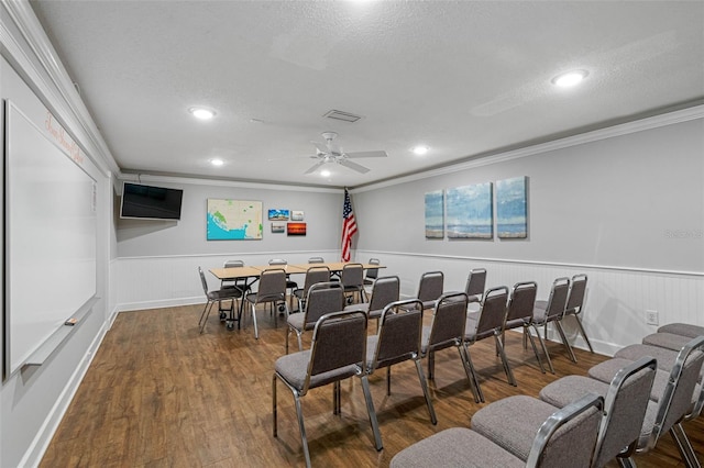 cinema room featuring visible vents, ornamental molding, wood finished floors, and wainscoting