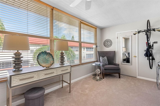 sitting room featuring light carpet, ceiling fan, baseboards, and a textured ceiling