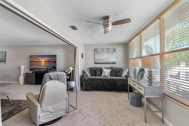 carpeted living room with a ceiling fan, baseboards, visible vents, and a textured ceiling