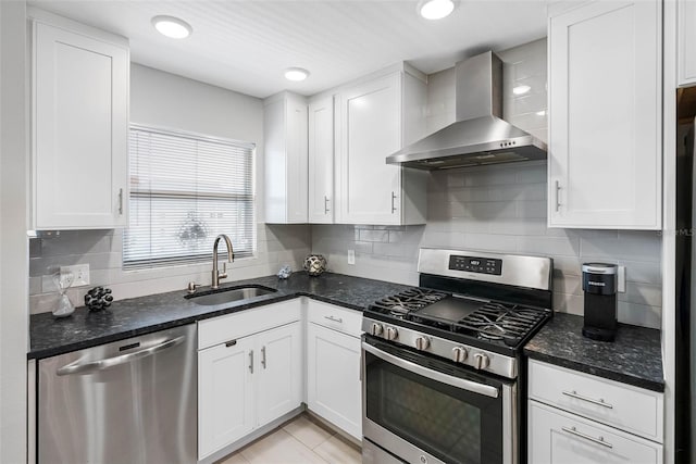 kitchen featuring stainless steel appliances, wall chimney range hood, a sink, and white cabinets