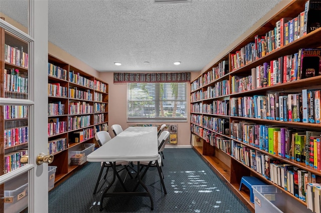 office area with baseboards, bookshelves, a textured ceiling, and wood finished floors