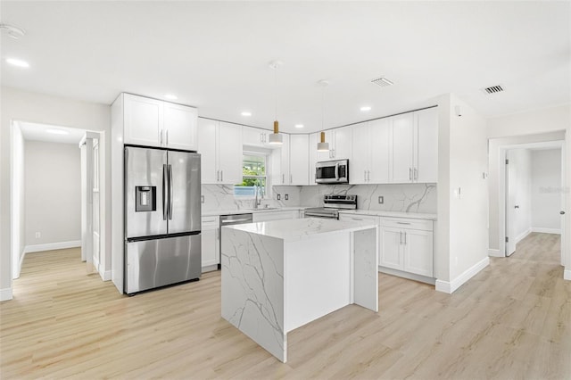 kitchen with stainless steel appliances, white cabinetry, and light stone countertops