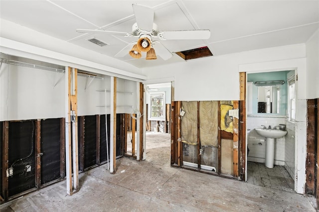 interior space with ceiling fan, a sink, and visible vents