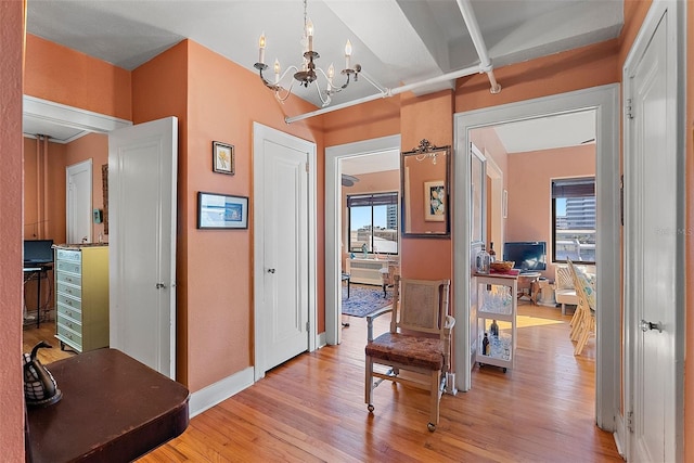 hall with an inviting chandelier, plenty of natural light, and light hardwood / wood-style floors