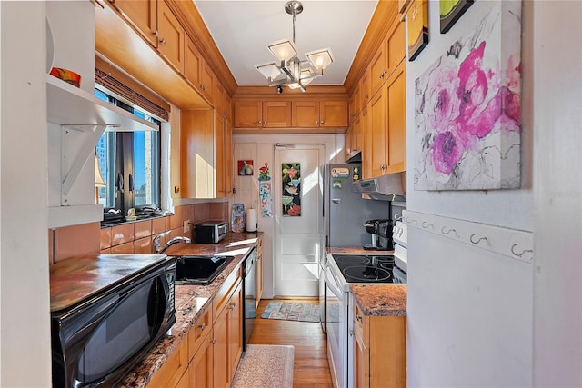 kitchen with sink, hanging light fixtures, black appliances, light stone countertops, and light wood-type flooring