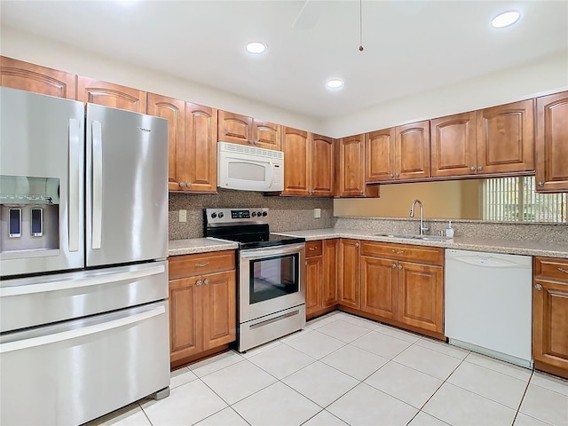 kitchen featuring light tile patterned flooring, sink, appliances with stainless steel finishes, light stone countertops, and decorative backsplash