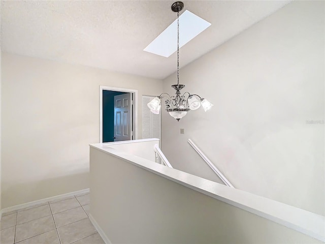 interior space with lofted ceiling with skylight, light tile patterned floors, a textured ceiling, and an inviting chandelier