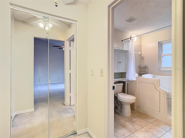 bathroom with shower / tub combo with curtain, tile patterned floors, toilet, washer / dryer, and a textured ceiling