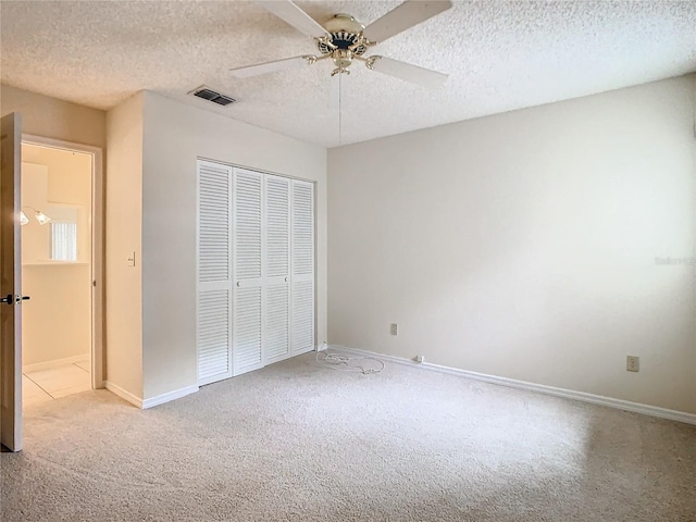 unfurnished bedroom featuring ceiling fan, light colored carpet, a closet, and a textured ceiling