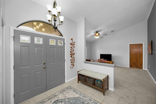 carpeted foyer entrance featuring lofted ceiling, ceiling fan with notable chandelier, and a textured ceiling