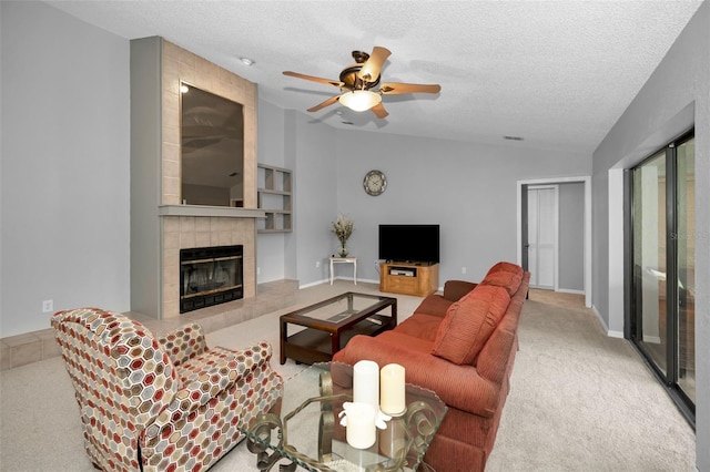 living room with lofted ceiling, a tile fireplace, ceiling fan, a textured ceiling, and light colored carpet