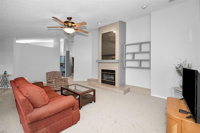 carpeted living room featuring ceiling fan, a fireplace, and a textured ceiling