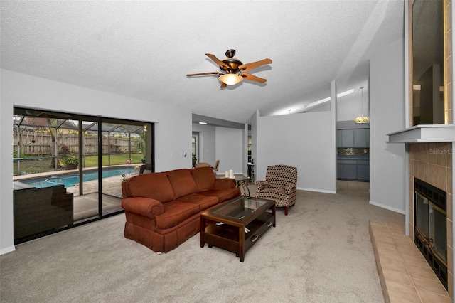 living room featuring a tiled fireplace, lofted ceiling, light colored carpet, and a textured ceiling