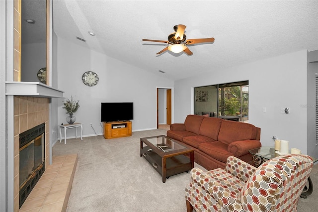 carpeted living room featuring a tile fireplace, lofted ceiling, ceiling fan, and a textured ceiling