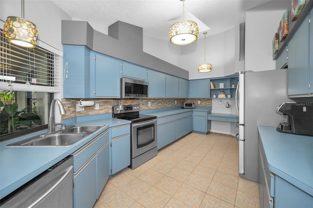 kitchen with sink, stainless steel appliances, decorative backsplash, blue cabinets, and decorative light fixtures