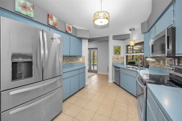 kitchen with light tile patterned floors, backsplash, stainless steel appliances, a textured ceiling, and blue cabinets