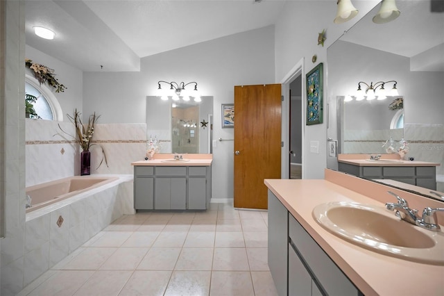 bathroom featuring a relaxing tiled tub, lofted ceiling, tile patterned flooring, and vanity