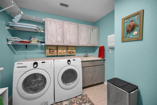 washroom with light tile patterned flooring, separate washer and dryer, sink, cabinets, and a textured ceiling